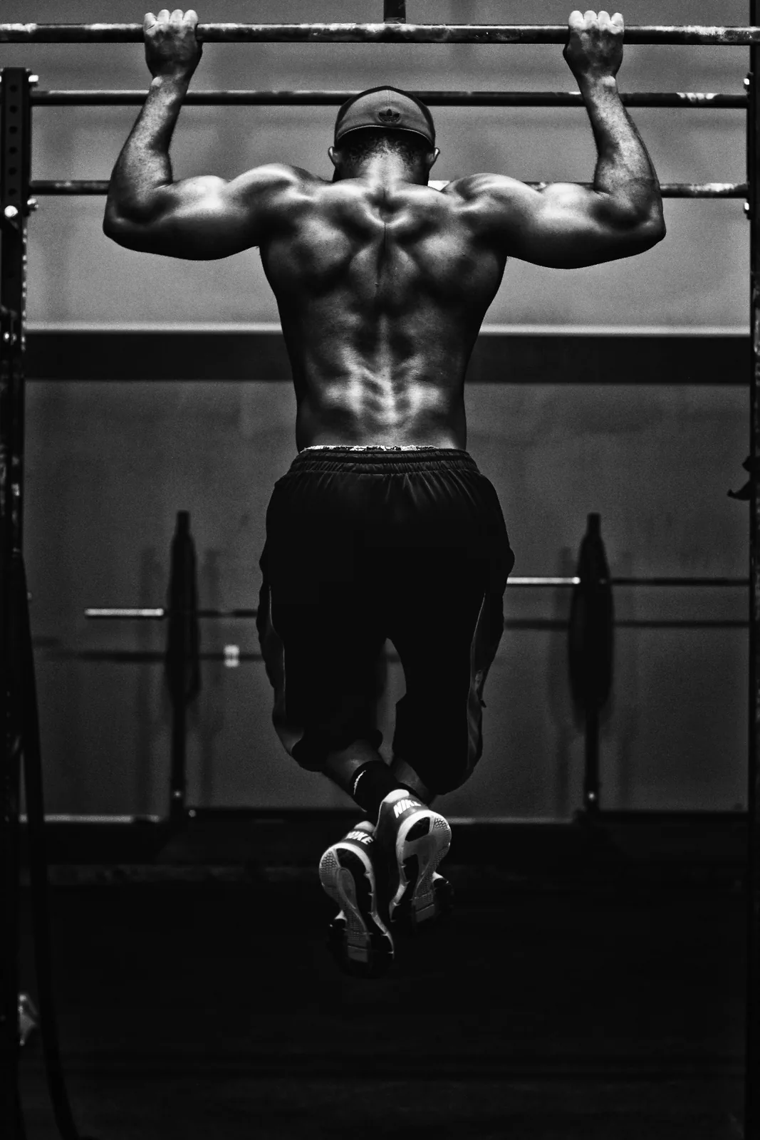 Athlete mid pull-up in a training rig, back and shoulders engaged.